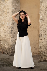 a lady in a black asymmetrical top and a pair of white wide leg pants